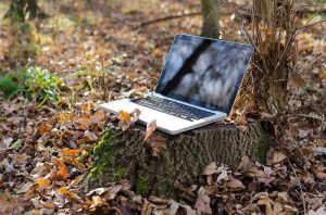 Laptop sitting on a stump outside